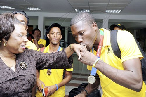 Ian Allen/Photographer
Johnathan Reid (right) gold medalist in the high jump at the just-concluded Carifta Games, kisses the hand of Minister of Sports and Culture Olivia Grange when she greets them at the airport.