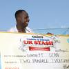 Mr. Dean smiles after receving his cheque for $200,000 from Olympic 400m hurdles champion , Melaine Walker.