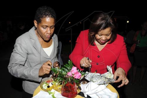 Rudolph Brown/Photographer
Janelle Brown (left) marketing and product manager, Retail Banking, Scotiabank, enjoys a bite with  Jackie Hamilton, acting promotions manager of Scotiabank.

******************************************************************** at the Wealth Magazine and Scotia DBG Investments Chicks and Balances Poolside party at Terra Nova Hotel in Kingston on Thursday, August 19-2010