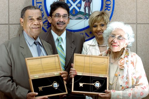 Ricardo Makyn/Staff Photographer
Phillip Duncan (left), former town clerk, displays the key to the city he received from the Kingston and St Andrew  Corporation (KSAC) on behalf of the late Marie Atkins, former mayor. Lorna Peralto (right), widow of the late Ryan Peralto, former parliamentarian and Kingston mayor, also received a key. Ryan Peralto Jr and Mishka Peralto watch from the background. The presentation took place during a parish council meeting at the KSAC Tuesday.