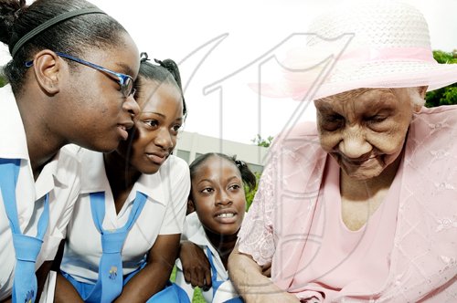 Rudolph Brown/Chief Photographer
Centenarian Catherine Reynolds tells her story to Merl Grove High School students (from left) Kristen Rhone, Tiffany Gilbert and Shaneek McPherson during the National Council for Senior Citizens/Ministry of Labour and Social Security Centenarians' Day celebration and Intergeneration Day at the council's offices in Kingston yesterday. Reynolds is 101 years old.