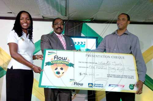 Ricardo Makyn/Staff Photographer.
Sharon Roper, marketing manager, Flow, hands over her company's commitment - the sum total of each goal scored in the Flow Champions Cup KO competition - to Whole Life Ministries' Andre Virtue (right), during the presentation ceremony at the Jamaica Football Federation (JFF) headquarters on Monday. Looking on is JFF president Captain Horace Burell.
