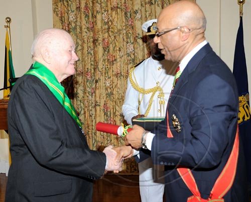 Rudolph Brown/Chief Photographer
Governor General, Patrick Allen (right) invests Desmond Blade with the Order of Jamaica, during the ceremony of investiture and presentation of National Honours and Award looking on Assisting the Governor General is his Aide de Camp, Captain Delando Coriah. at Kings House, St Andrew on Tuesday. May 12-2009