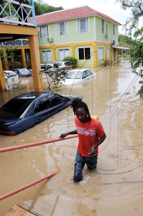 Norman Grindley/Chief Photographer
A man makes his way out of a flooded car park at Milk River Hotel and Spa in Clarendon yesterday.