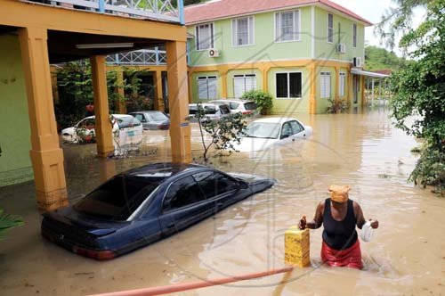Norman Grindley /Chief Photographer
A woman trudges through the inundated car park at the Milk River Hotel and Spa.

make his way out of a flooded car park at Milk River hotel and Spa in Clarendon yesterday.
