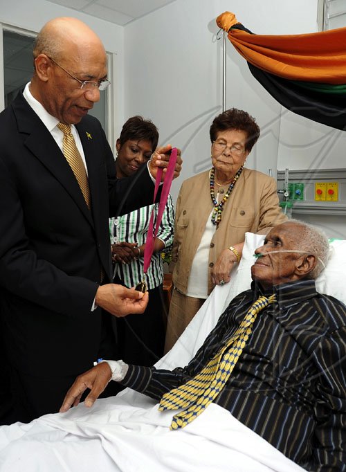 Ian Allen/Staff Photographer
Sir patrick Allen left, Governor General along with Olilvia Grange centre, Minister of Youth, Sports and Culture presented with a Musgrave Gold Medal and citation to Wycliffe Bennett at an award ceremony at the University of the West Indies Hospital. Wycliffe Bennett who has been ailing for some time was also visited by  scores of admirers who attended the ceremony. Looking on is his wife Dr. Hazel Bennett.