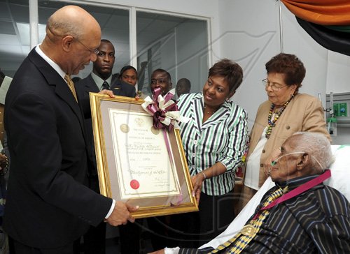 Ian Allen/Staff Photographer
Sir Patrick Allen left, Governor General along with Olilvia Grange centre, Minister of Youth, Sports and Culture presented with a Musgrave Gold Medal and citation to Wycliffe Bennett at an award ceremony at the University of the West Indies Hospital. Wycliffe Bennett right and his wife Dr. Hazel Bennett second right.Wycliffe Bennett who has been ailing for some time was also visited by  scores of admirers who attended the ceremony.
