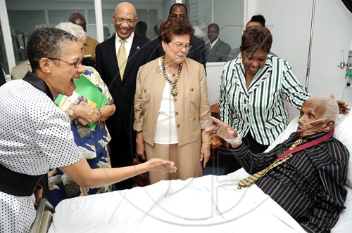 Ian Allen/Staff Photographer
Wycliffe Bennett (right) shows his delight when Fae Ellington (left) visits during The Institute of Jamaica's Musgrave Medal award ceremony held at the University of the West Indies Hospital. Bennett was presented with a Gold Medal and a citation by Governor General Sir Patrick Allen (third left) and Sports Minister Olivia Grange for his contribution to the development of the arts in Jamaica. Looking on are Hazel Bennett (centre) and Jean Smith (partially hidden).