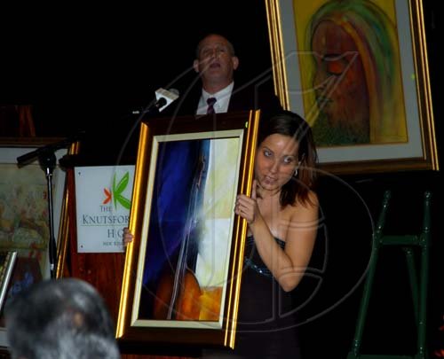 Winston Sill / Freelance Photographer
Jamaicans For Justice (JFJ) in association with Knutsford Court Hotel presents their Gala Dinner, Art and Collectibles Auction, held at Knutsford Court Hotel, Ruthven Road on Friday night June 4, 2010. Here are Deirdxre Gomes holds the George Rodney work that fetch the highest price for the night of $160,000.00. In background is Auctioneer Douglas Reid.
