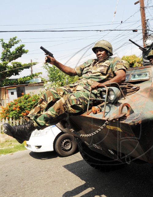 Norman Grindley /Chief Photographer
A soldier slides from an armoured vehicle as he gets ready for action in West Kingston on Monday.