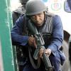 Norman Grindley /Chief Photographer
A policeman takes cover behind a vehicle as lawmen and gunmen in the Hannah Town area of West Kingston yesterday.