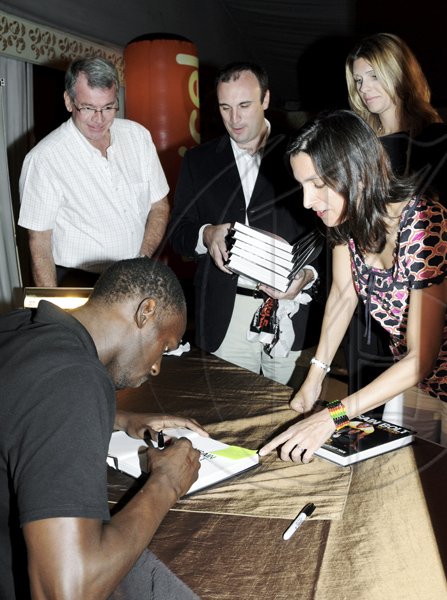 Winston Sill / Freelance Photographer
World 100 and 200m record holder Usain Bolt (left) signs an autograph for a reader of his biography at his book launch on Thursday night. The book launch and signing of his book, "My Story 9.58-- Being The World's Fastest Man",  was held at the Terra Nova All-Suite Hotel on Waterloo Road.