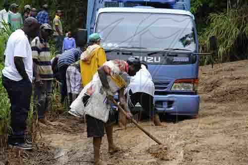 Ian Allen/Photographer
Residents of Guava Ridge in rural St.Andrew help to clear a vehicle that was stuck in mud from landslides caused by the overnight rains in the area.