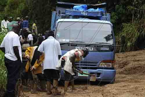 Ian Allen/Photographer
Residents of Guava Ridge in rural St.Andrew help to clear a vehicle that was stuck in mud from landslides caused by the overnight rains in the area.